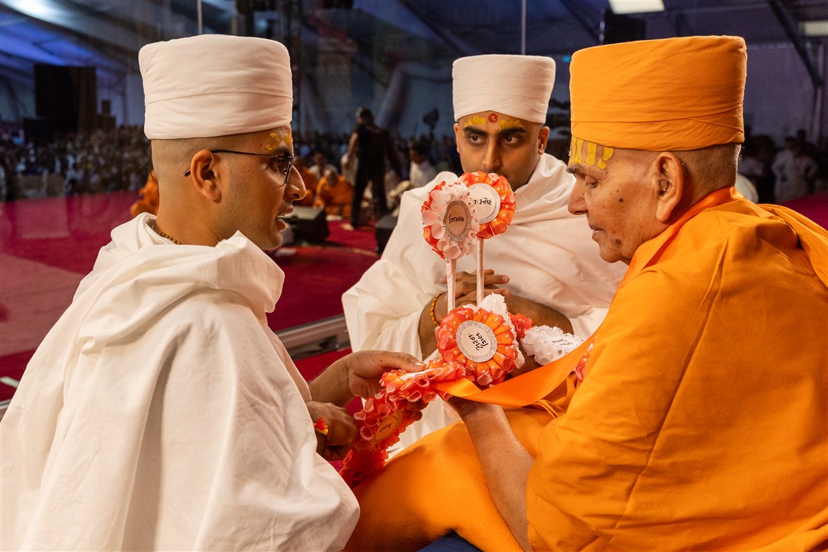 The new parshads offer Swamishri a decorative garland