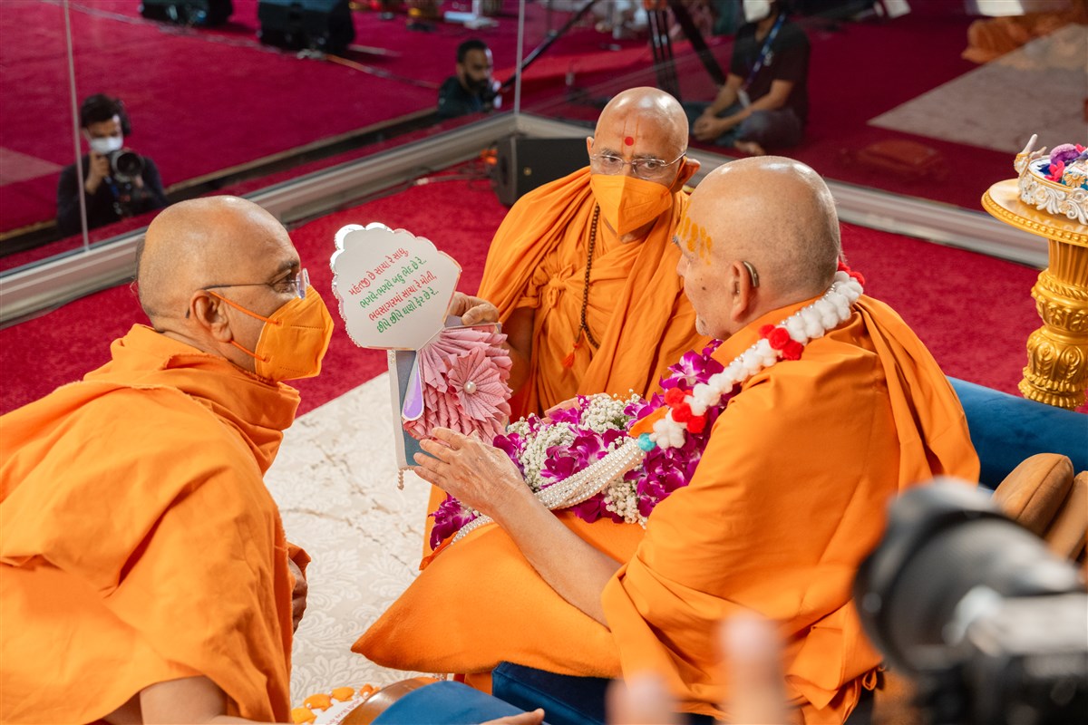 Gnanpriyadas Swami and Narayanmunidas Swami present Swamishri with a garland and a decorative card