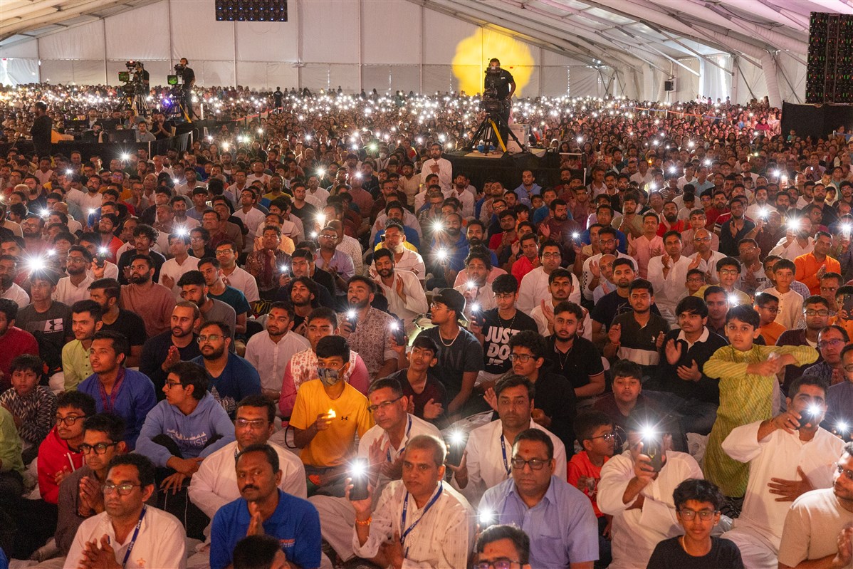 Devotees join the evening arti using phone flashlights