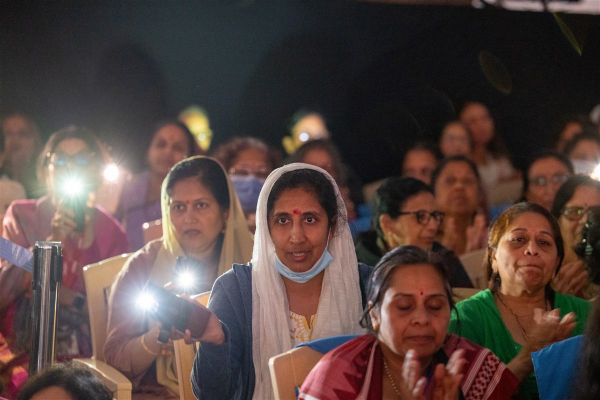 Devotees join the evening arti using phone flashlights
