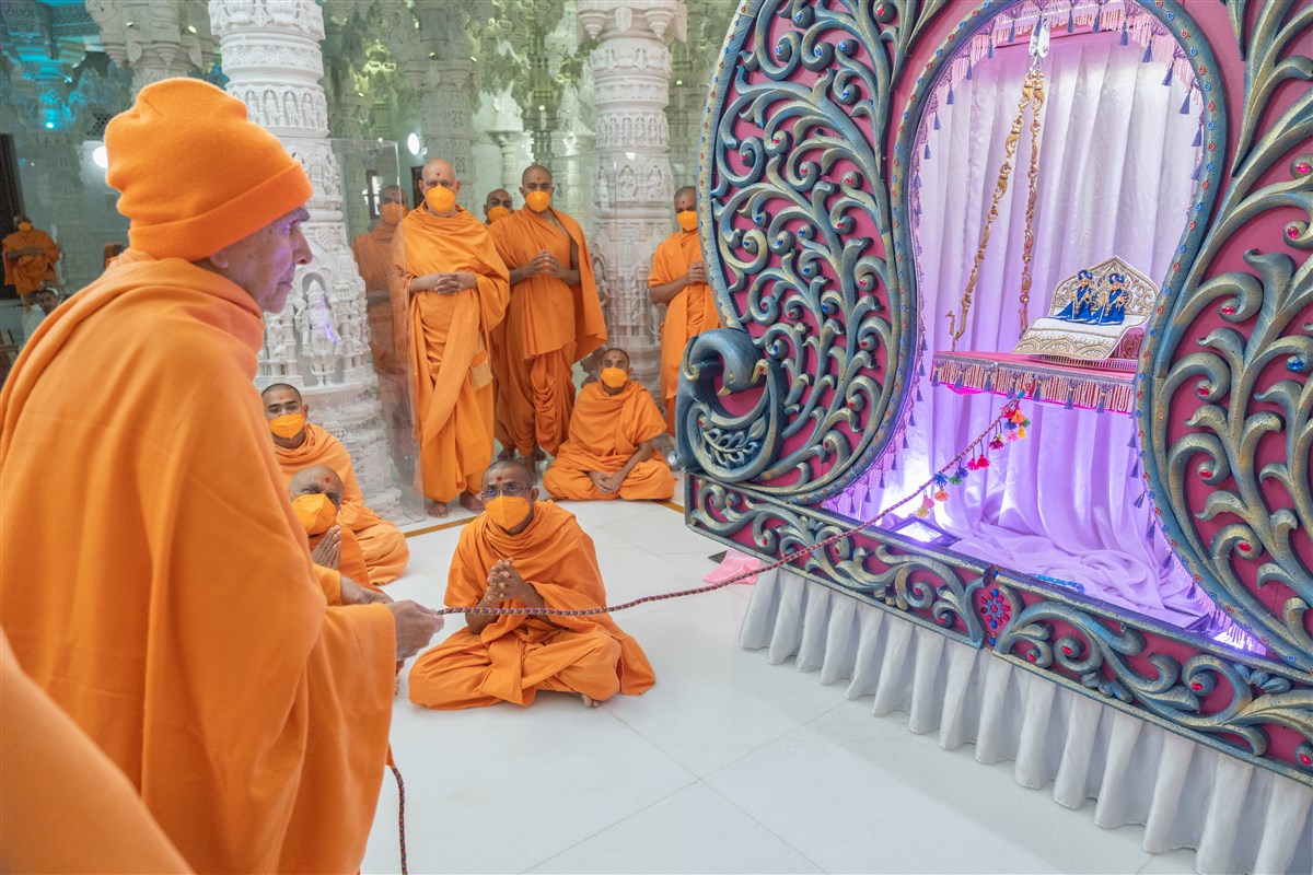 Swamishri lovingly swings Shri Harikrishna Maharaj and Shri Gunatitanand Swami in a traditional hindolo