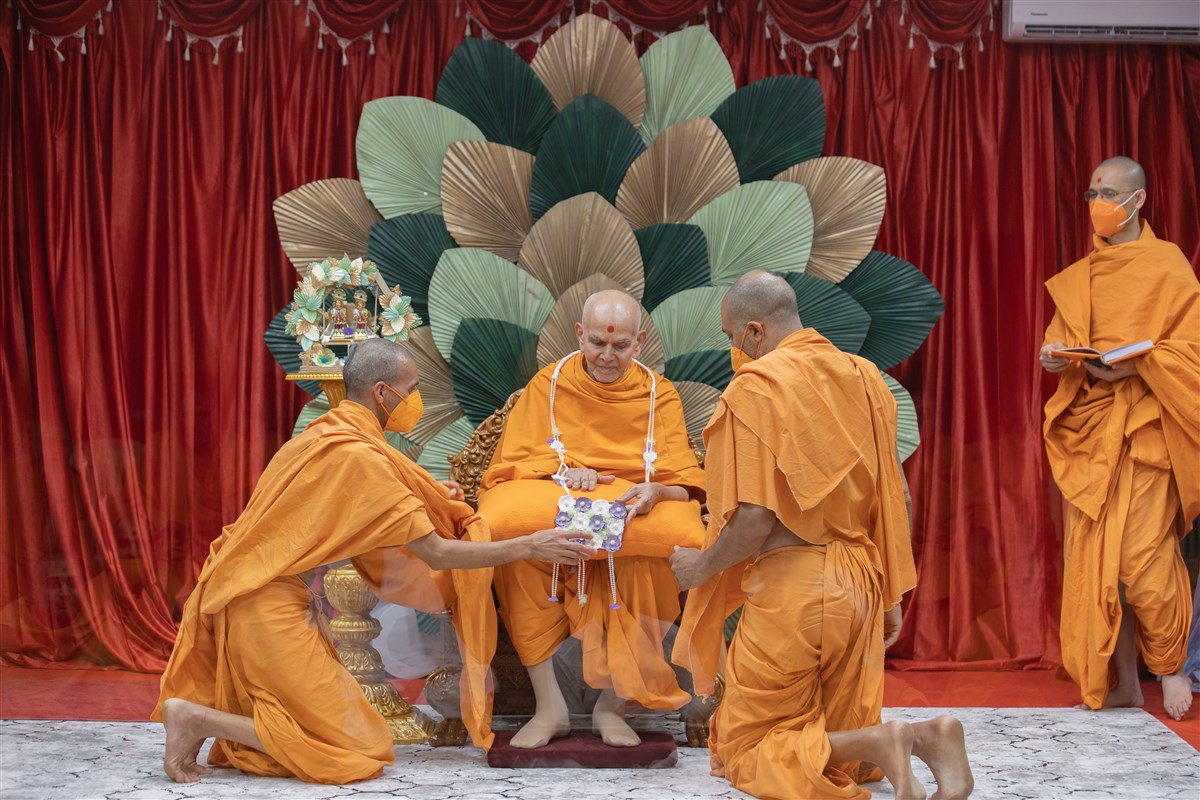Swamis present Swamishri with a garland..