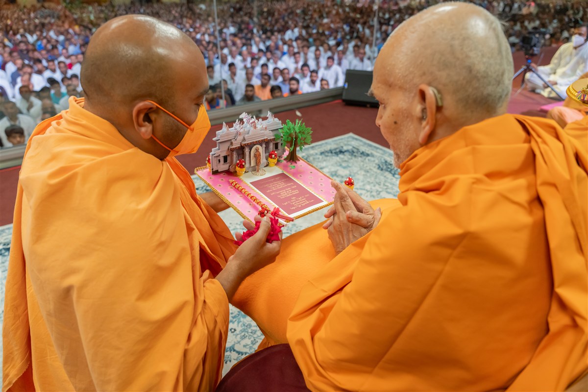 Swamishri sanctifies the invitation card of the Shri Nilkanth Varni murti-pratishtha