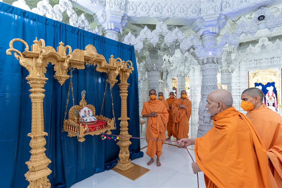 Swamishri gently sways Shri Harikrishna Maharaj and Shri Gunatitanand Swami in a traditional hindolo