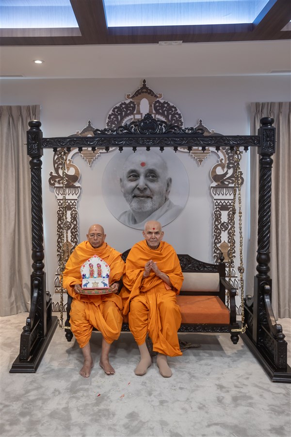 Swamishri and Sadguru Tyagvallabhdas Swami in a hindolo with Shri Harikrishna Maharaj and Shri Gunatitanand Swami Maharaj