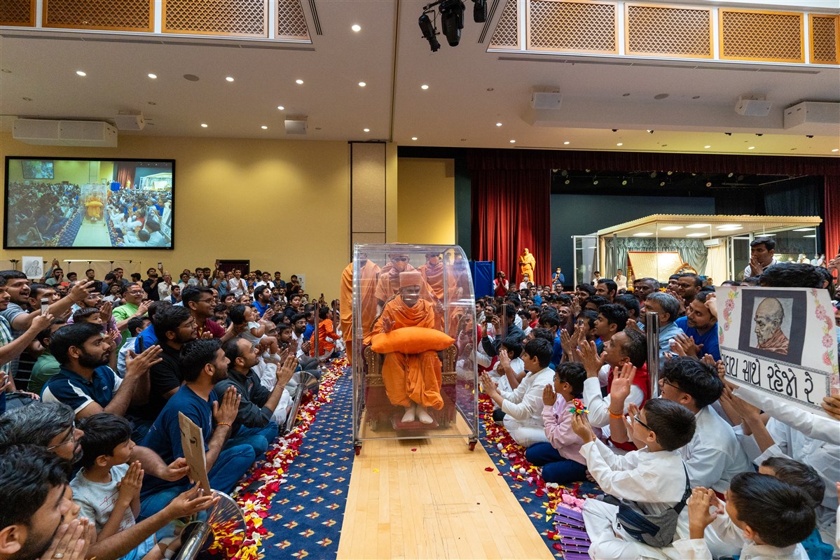 Swamishri blesses devotees as he departs from the assembly hall
