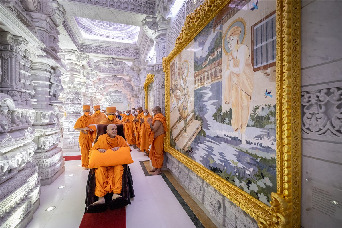 Swamishri gazes at one of the murals as he makes his way to his residence