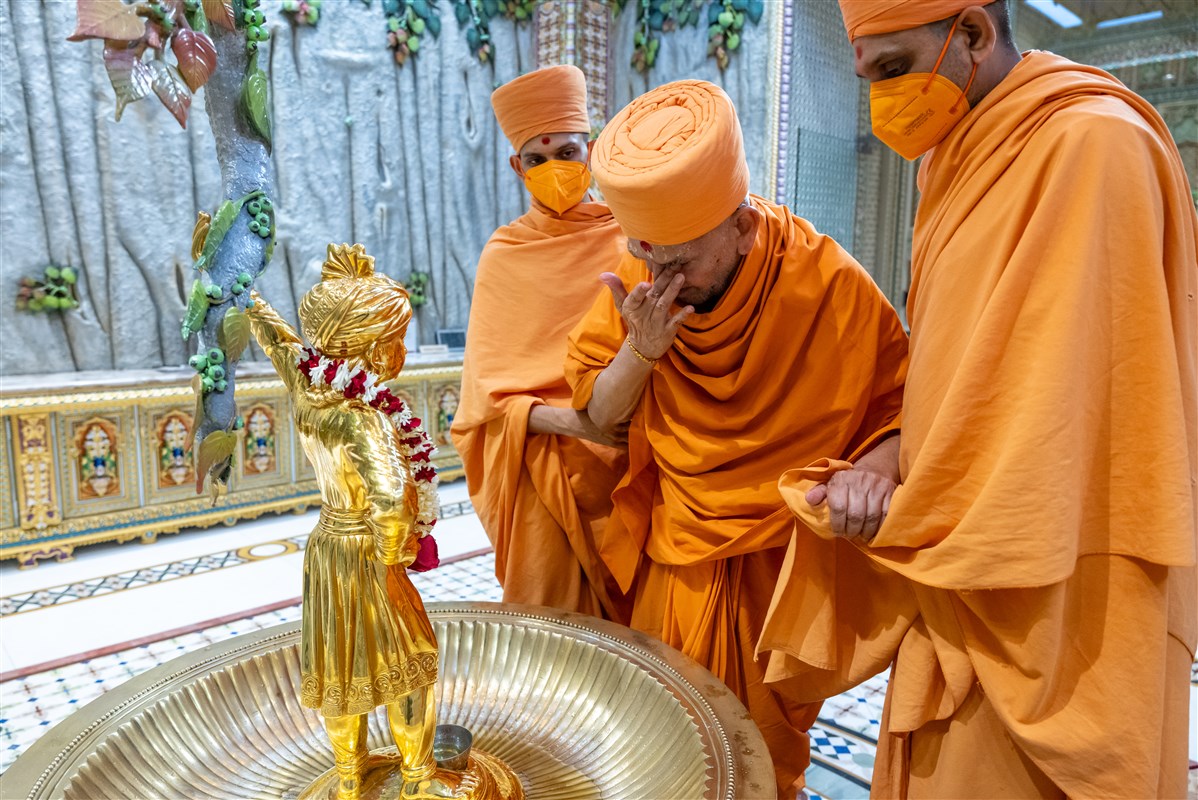 Swamishri reverently touches the holy feet of Shri Ghanshyam Maharaj