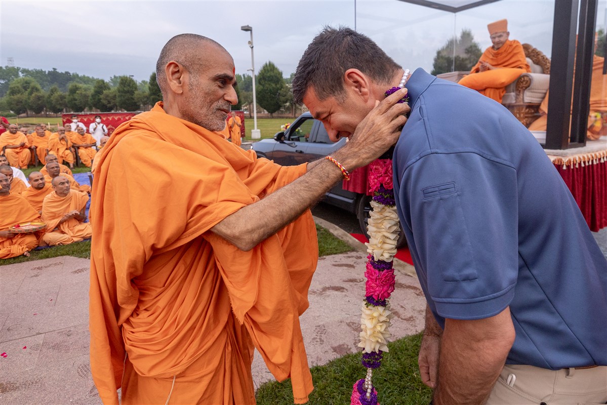 Robbinsville Township Mayor David Fried, who had come to welcome Swamishri, is adorned with a garland by Anandswarupdas Swami
