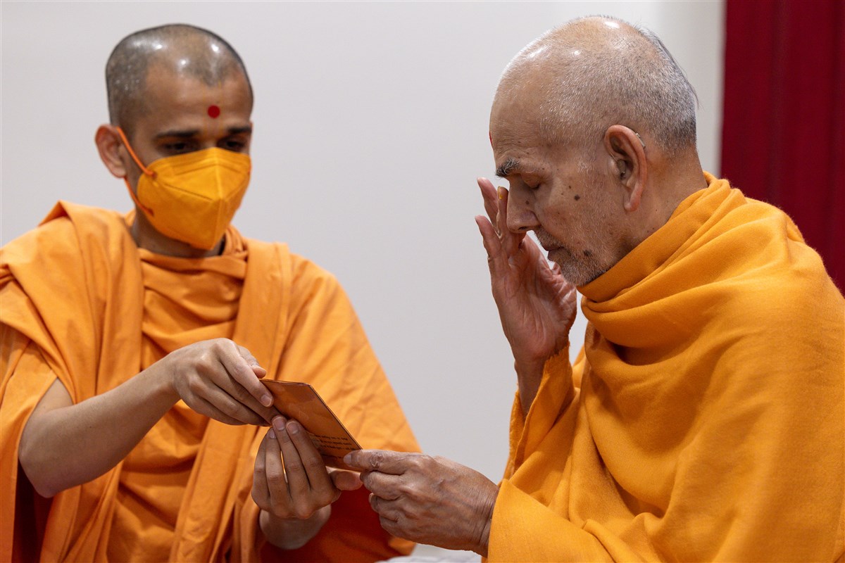 Swamishri reverently touches the holy feet of Bhagwan Swaminarayan and Gunatitanand Swami