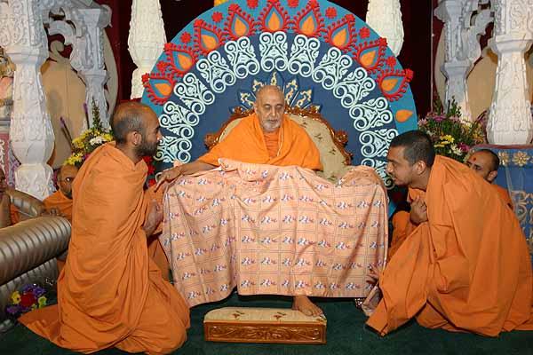 Swamishri is presented with a shawl with niyams taken by the San Jose Mandal written on it. 