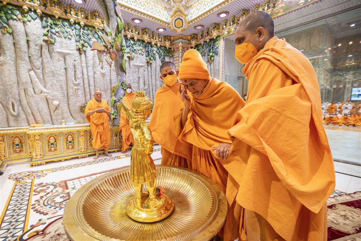 Swamishri touches the holy feet of Shri Ghanshyam Maharaj after the abhishek ritual to imbibe His blessings