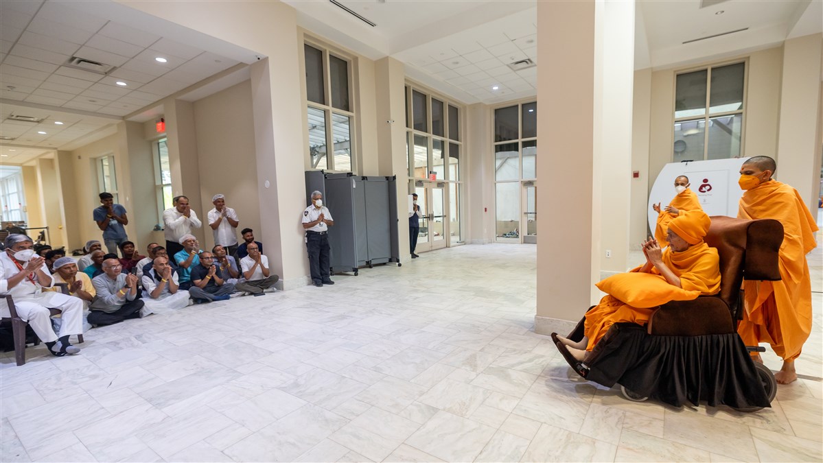 Devotees engrossed in Swamishri's darshan as he moves through the corridor