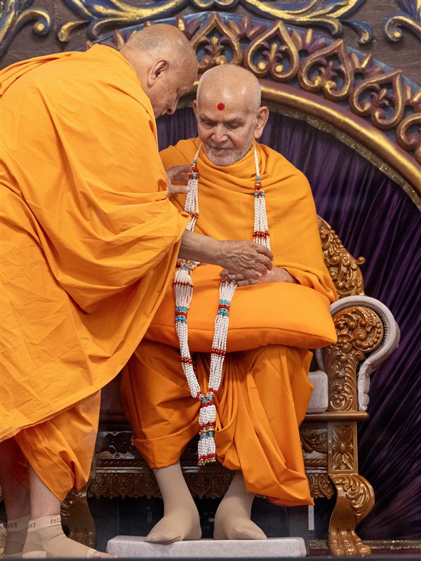 Sadguru Ishwarcharandas Swami presents a garland to Swamishri