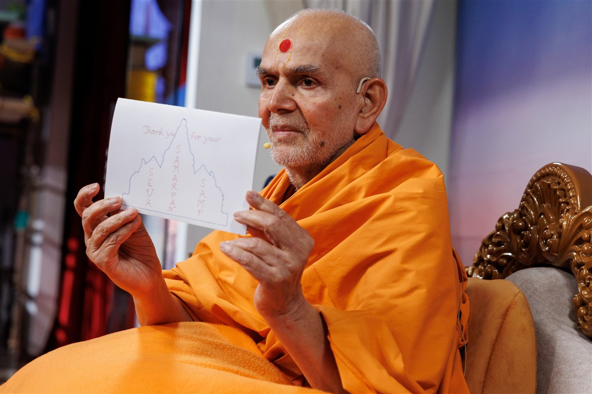 Swamishri displays a special card he created for the volunteers