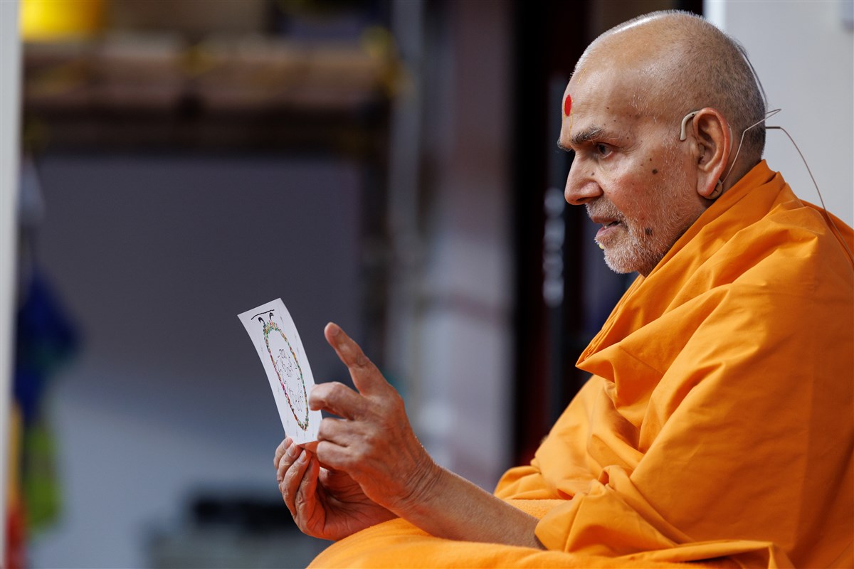 Swamishri reads the handmade card that he created for the volunteers