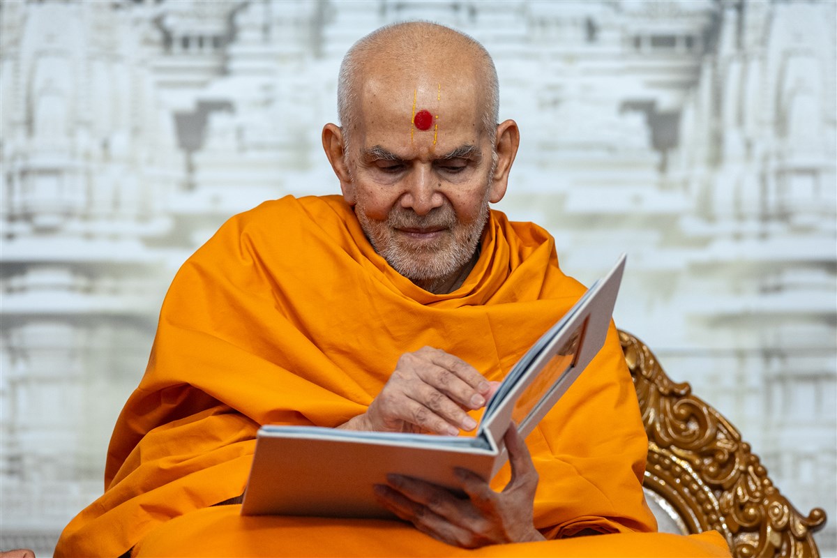 Swamishri blesses a book authored by female volunteers, which showcases the virtues of volunteers