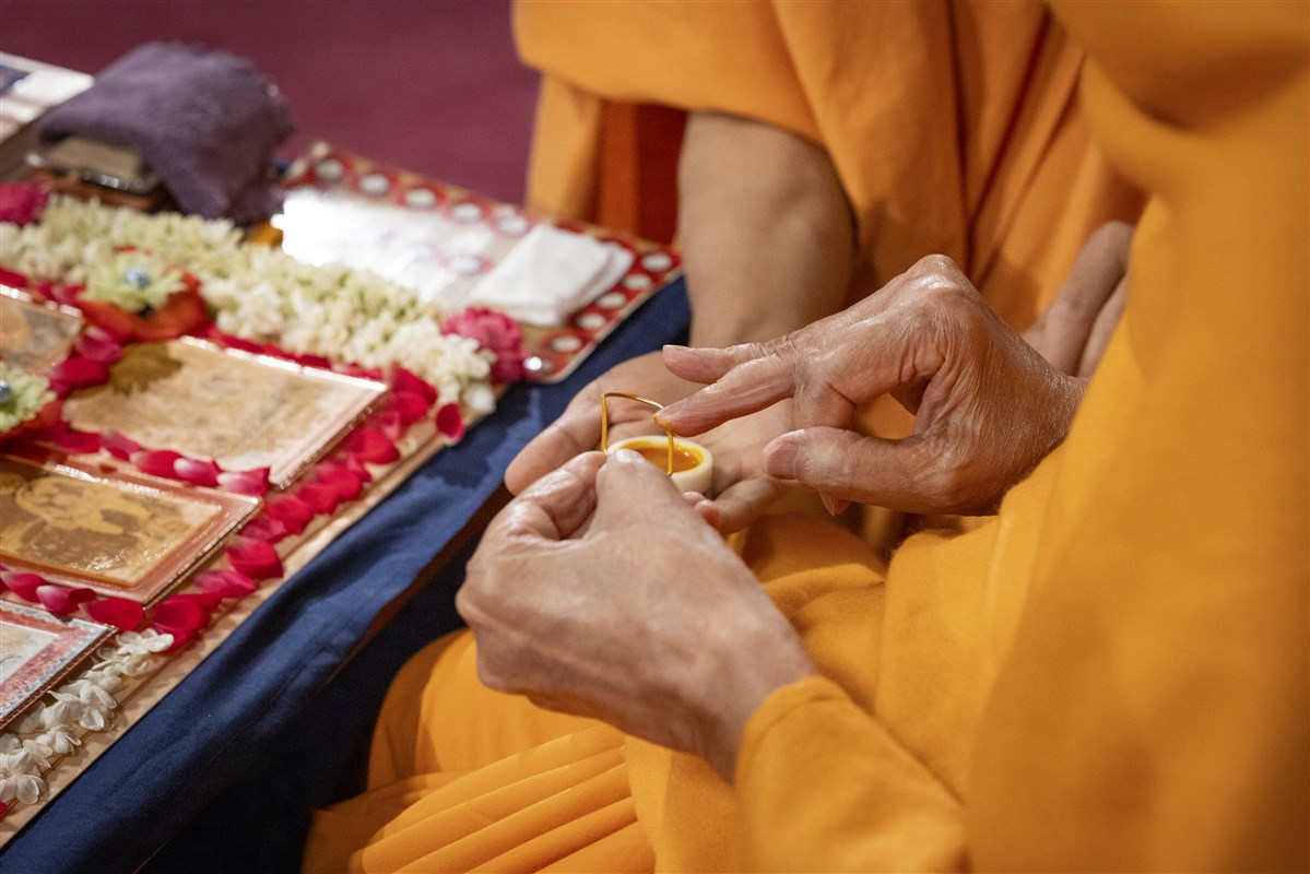 Swamishri commences his morning puja by applying sandalwood paste for the tilak