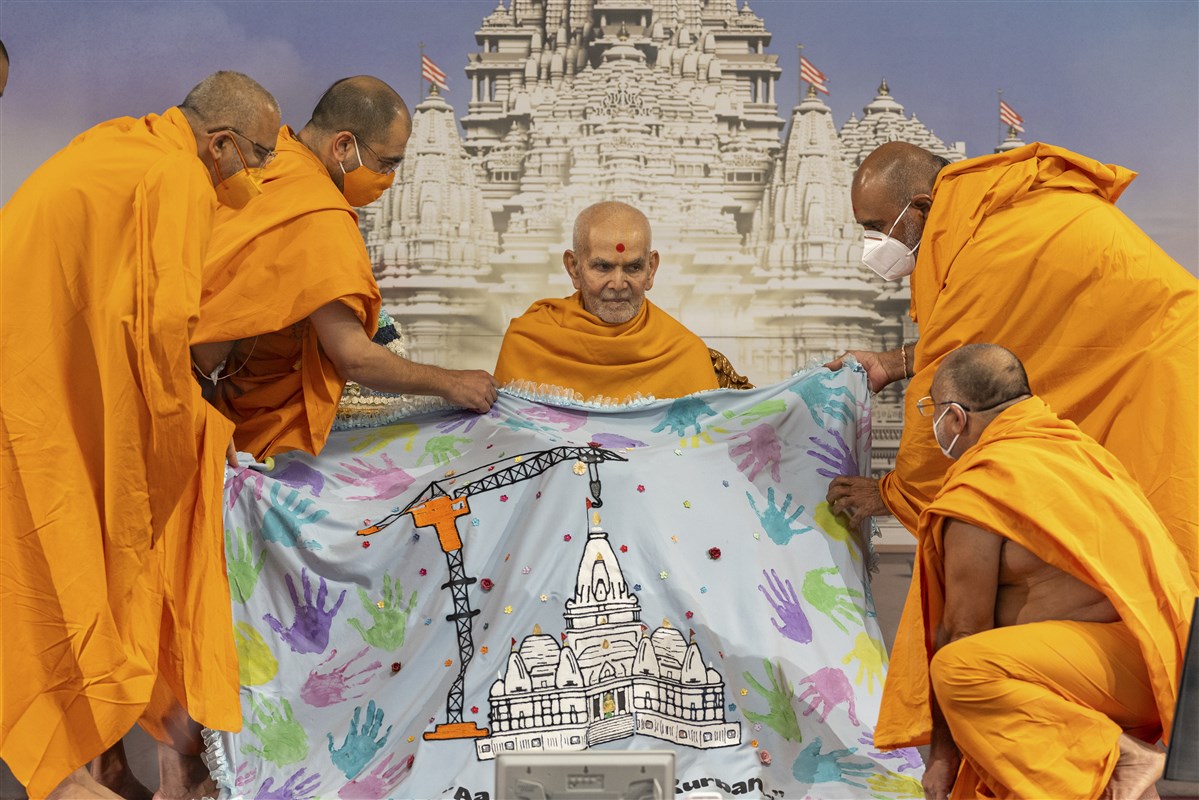 Swamis present Swamishri with a decorative shawl