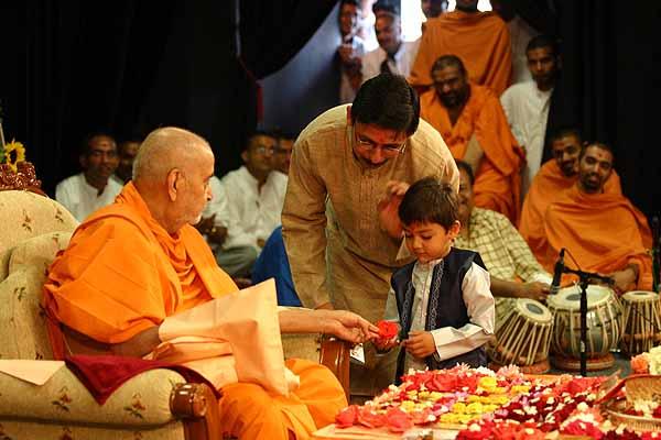 Swamishri gives a flower to a child that narrated a story during his pooja 