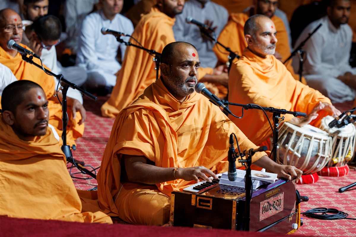 A swami sings a kirtan in Swamishri's puja