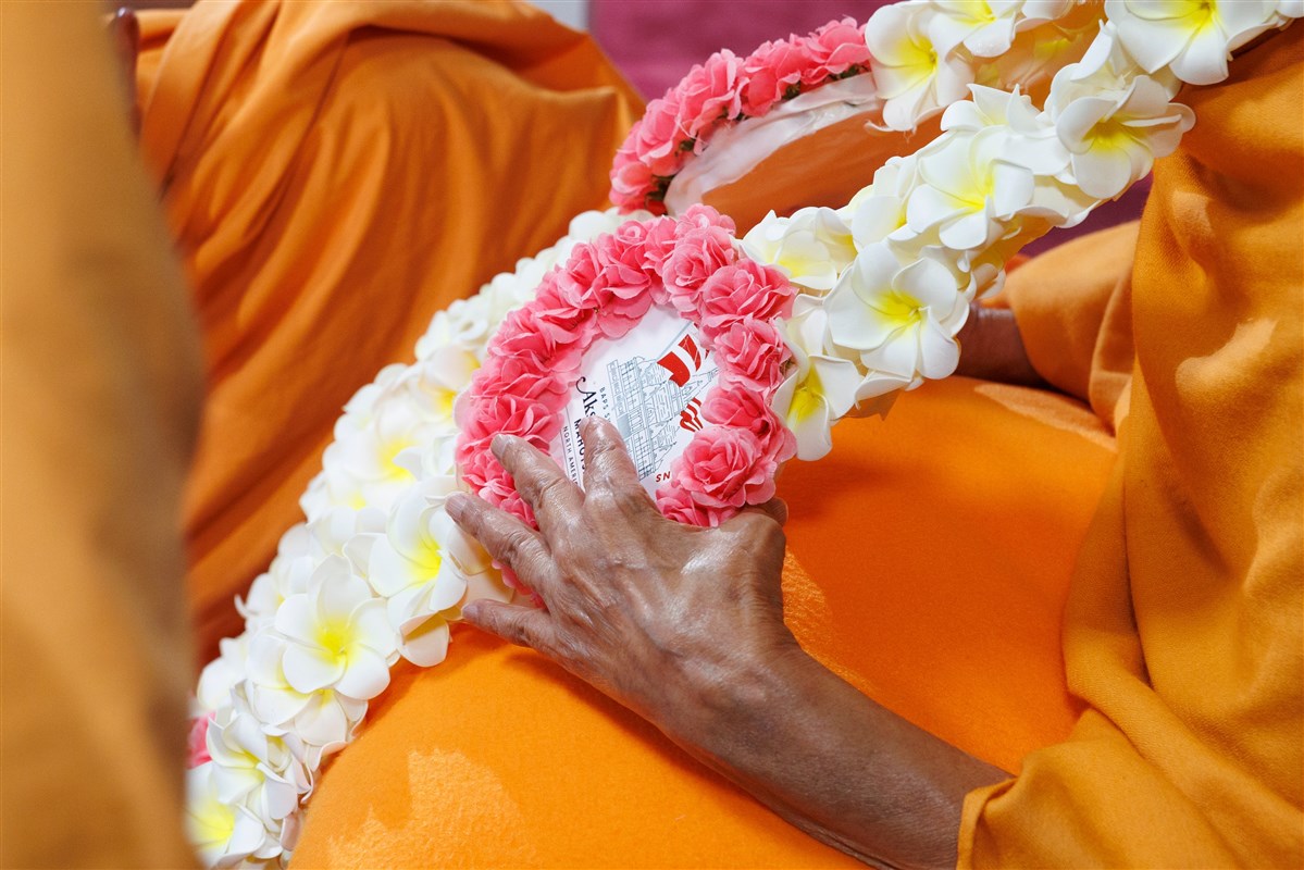 Swamishri bestows his blessings upon everyone involved in creating the garland by gently touching it