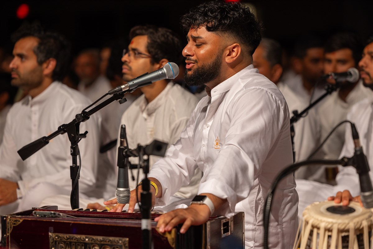A youth offers kirtan bhakti during Swamishri's puja
