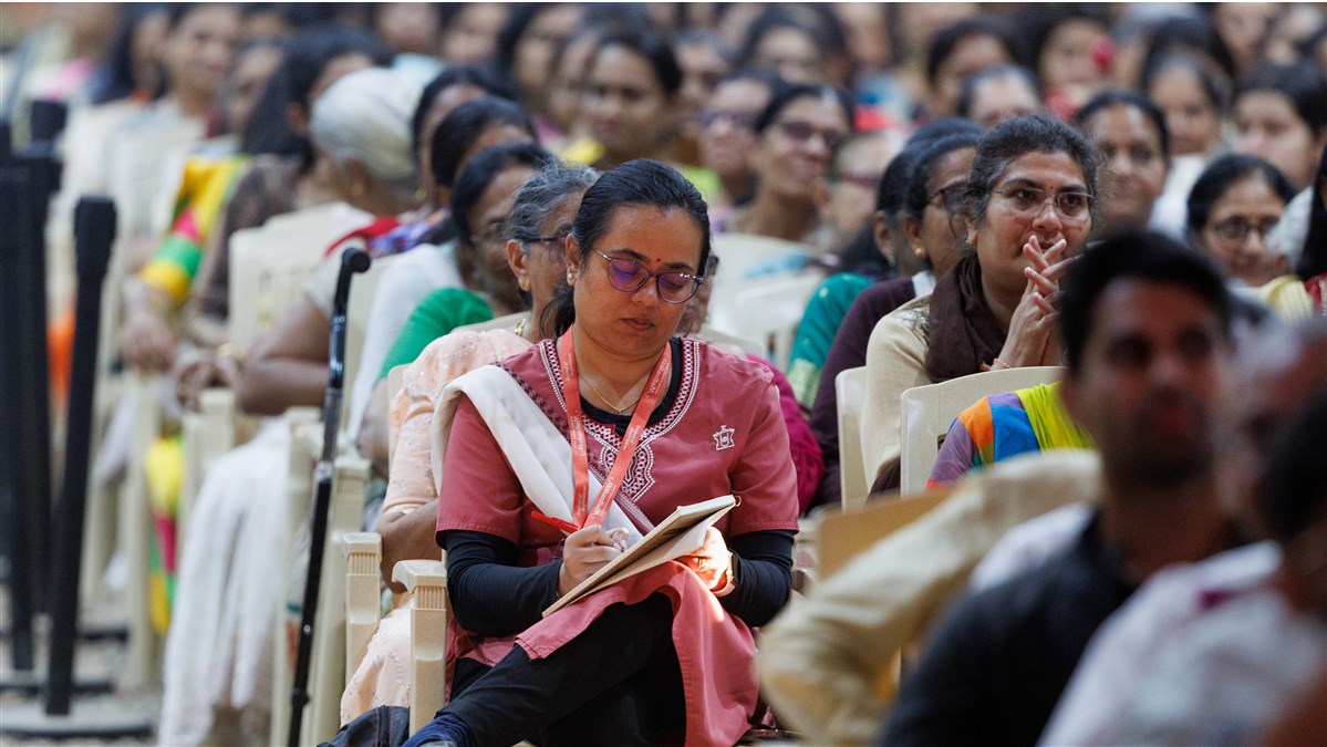 A devotee writes notes during the assembly