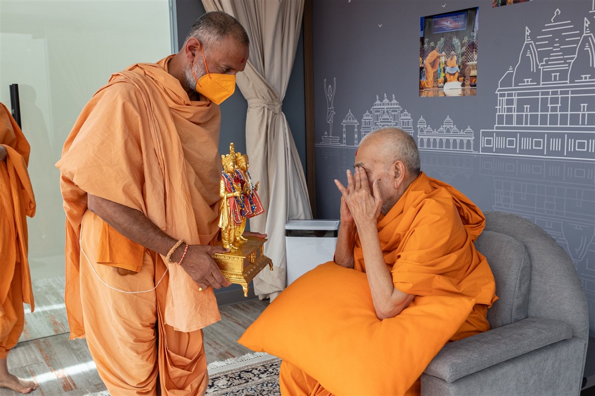 Swamishri touches his eyes after touching the feet of Shri Akshar Purushottam Maharaj. This Hindu practice of reverence and humility is performed to purify oneself and seek blessings