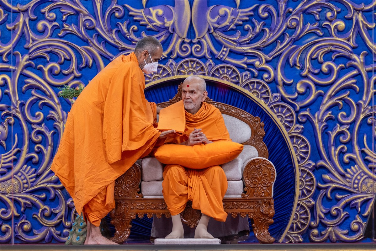 Anandswarupdas Swami offers a gataryu (upper garment) to Swamishri