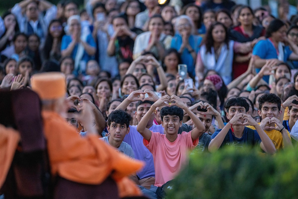 Children express their feelings towards Swamishri by creating a heart shape with their hands
