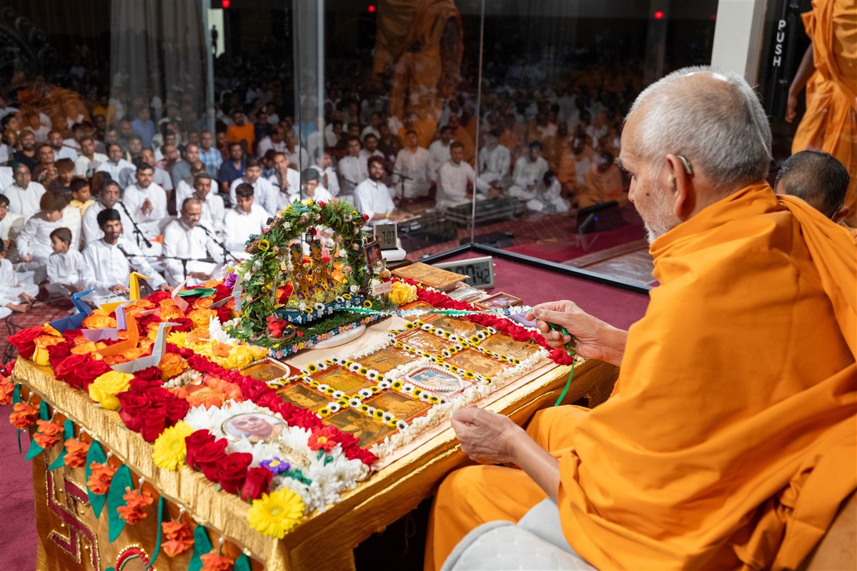 Swamishri gently sways Shri Harikrishna Maharaj and Shri Gunatitanand Swami in a traditional hindolo