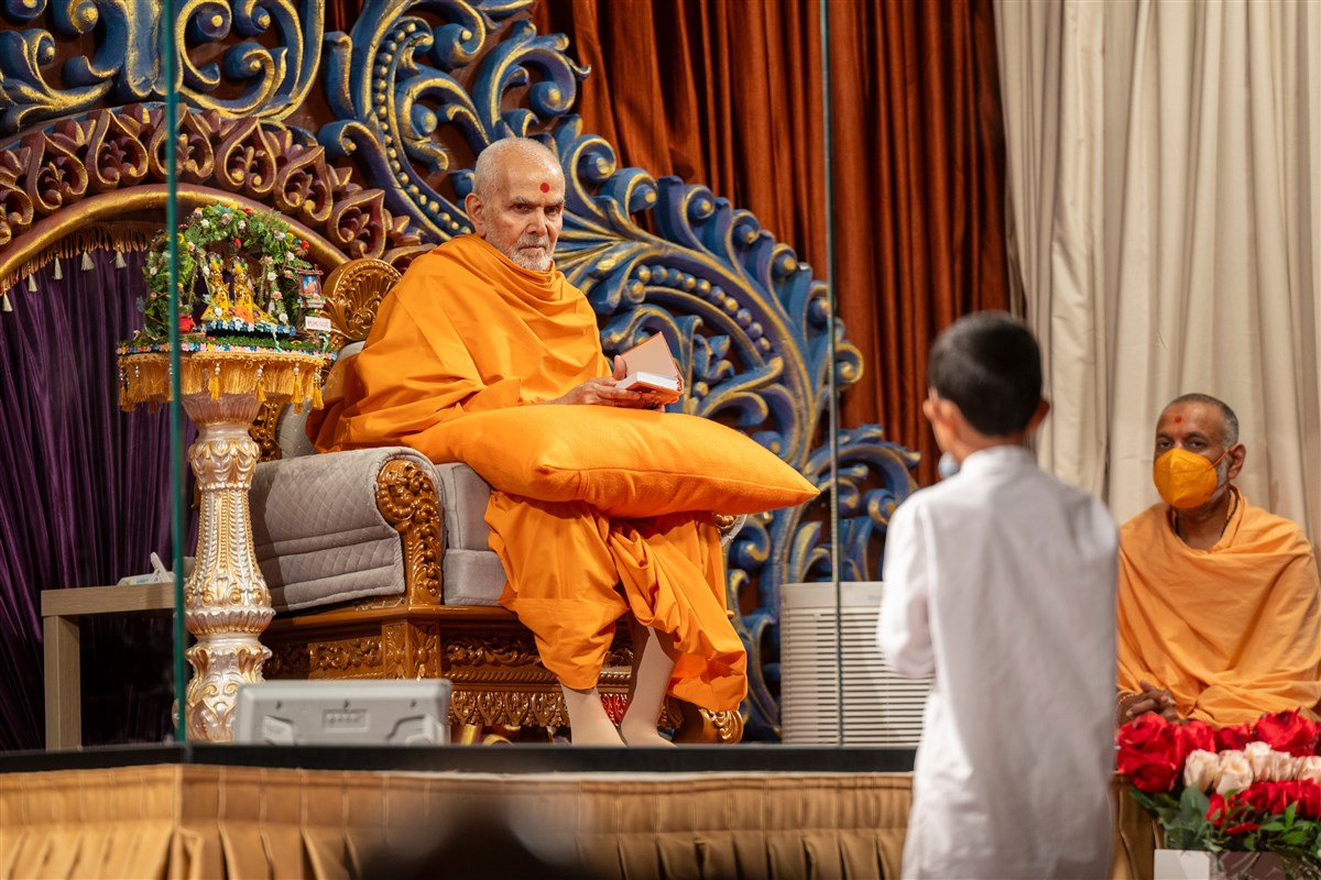 Swamishri glances at a child reciting scriptural passages