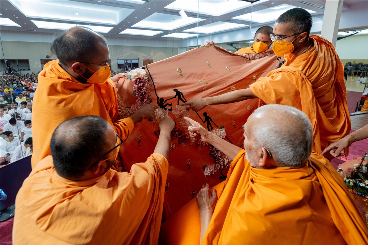 Swamishri looks at a shawl presented to him