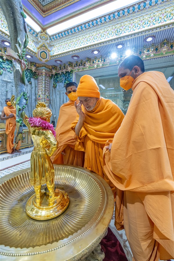 Swamishri touches his eyes after touching the feet of Shri Ghanshyam Maharaj