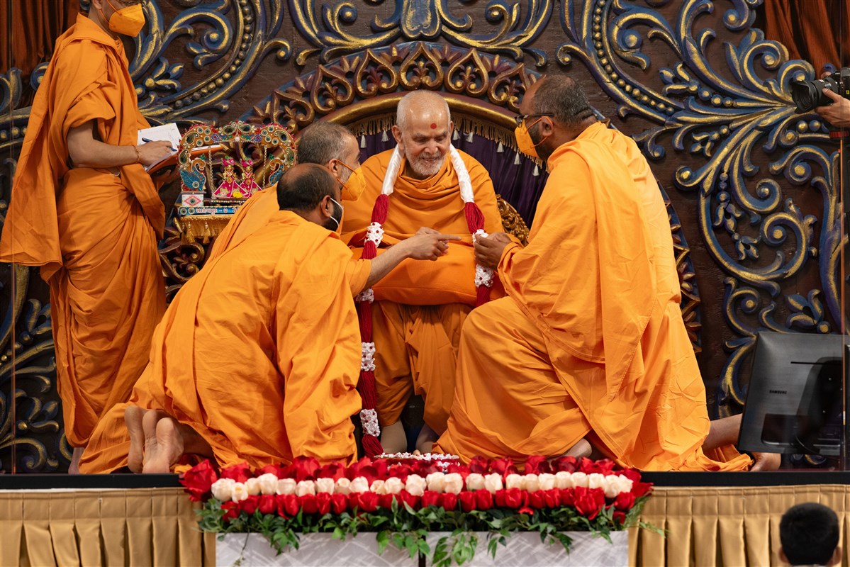 Swamis honor Swamishri with a decorative garland