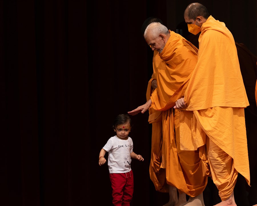 A child comes up to Swamishri after the puja, and he blesses him