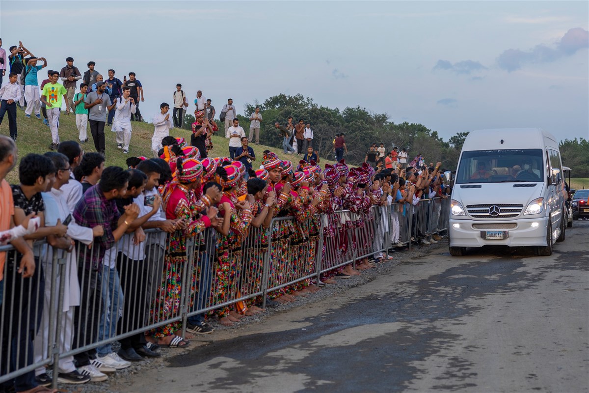 Devotees eagerly line up along the path of Swamishri's car for his darshan