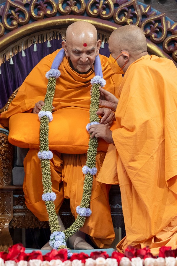 Swamishri listens attentively to Pujya Brahmaviharidas Swami after he garlands him