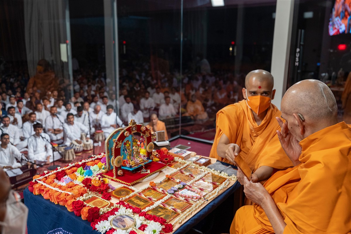 Swamishri reverently touches the holy feet of Shri Akshar Purushottam Maharaj