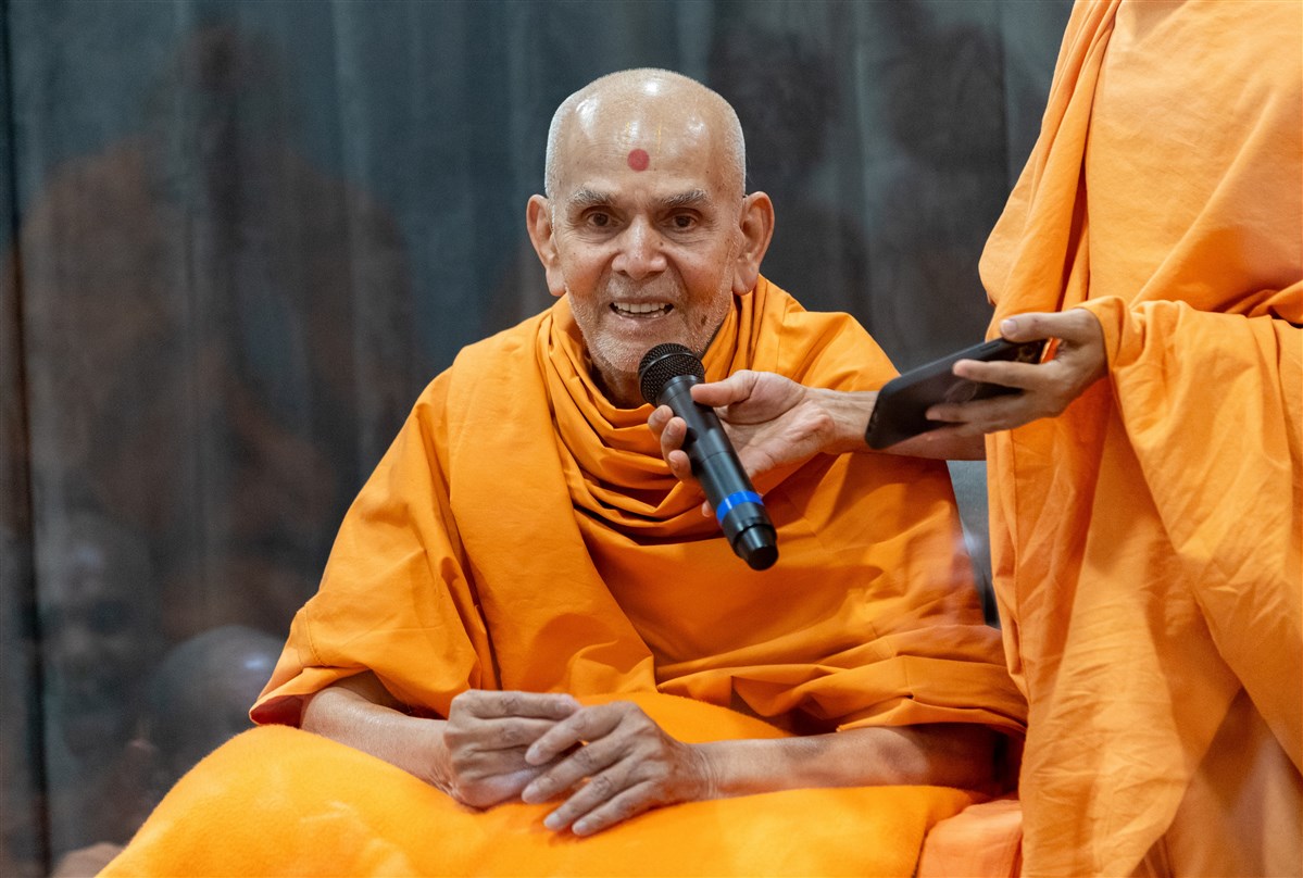 Swamishri shares a light moment with the swamis during the afternoon assembly