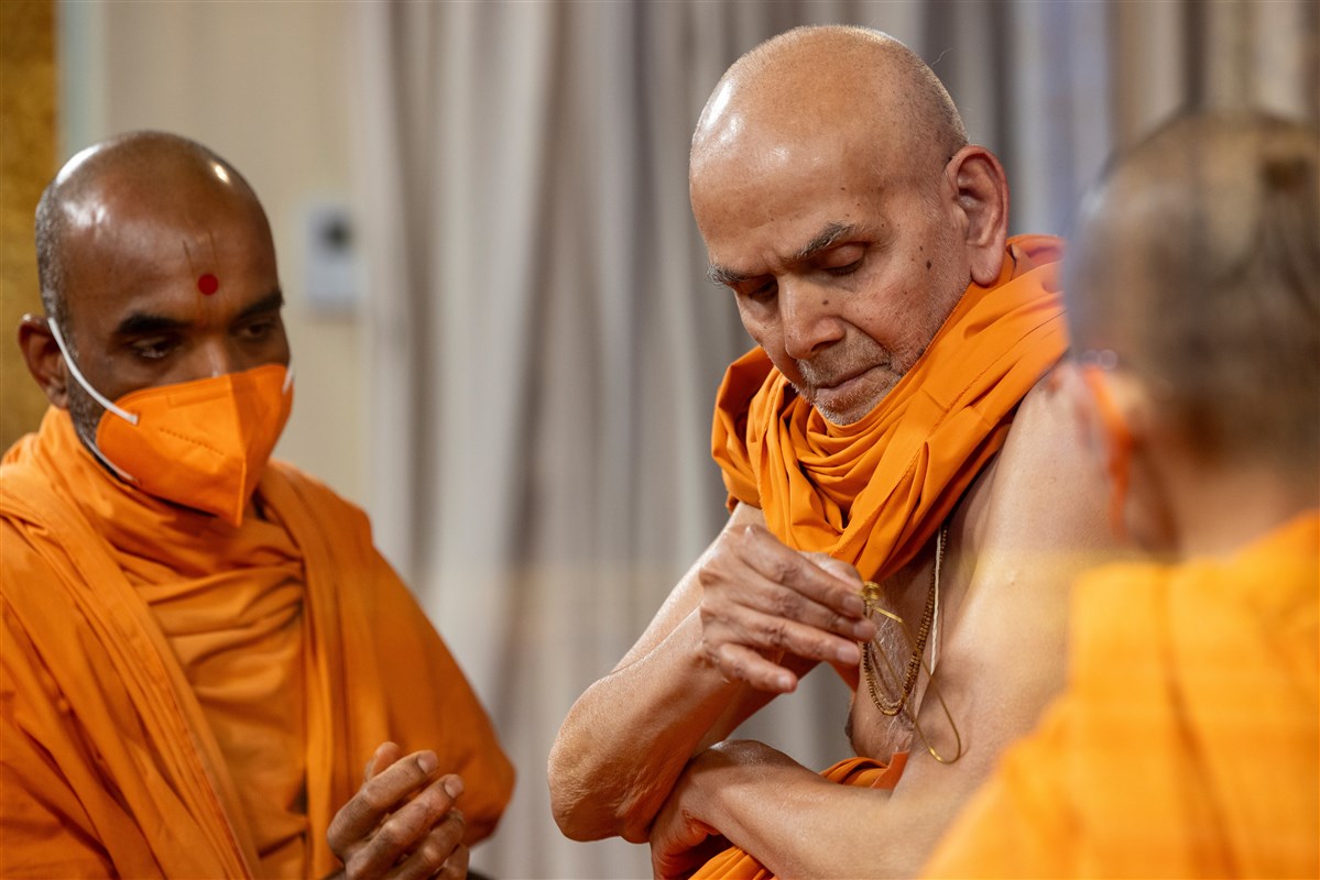 Swamishri applies a tilak on his arm