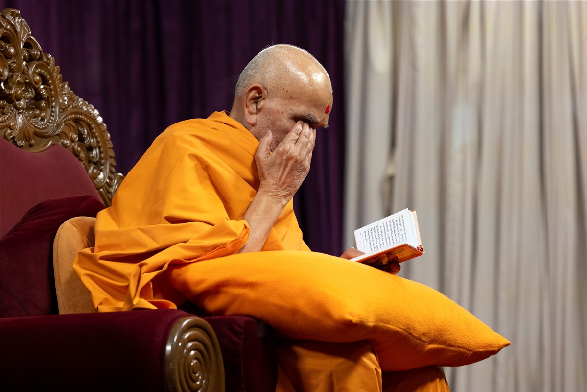 Swamishri reverently touches his eyes after darshan of a murti in the Satsang Diksha scripture