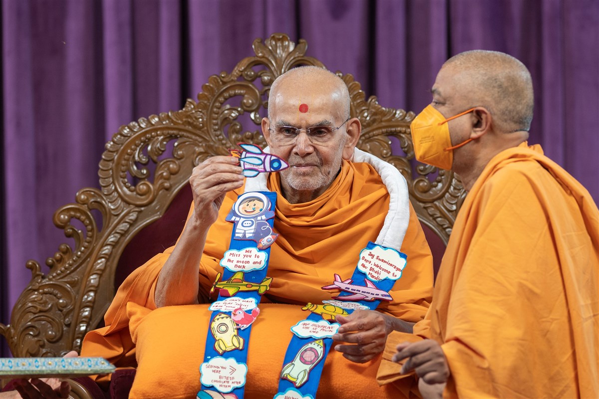 Swamishri observes the invitation card presented to him