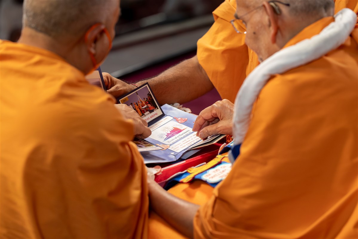 Swamishri observes the invitation card presented to him