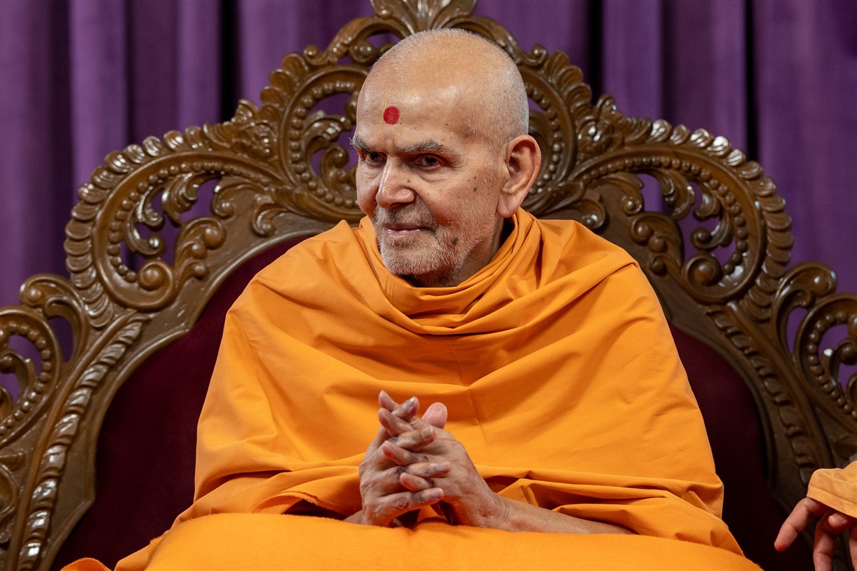 Swamishri listens to announcements after the morning discourse
