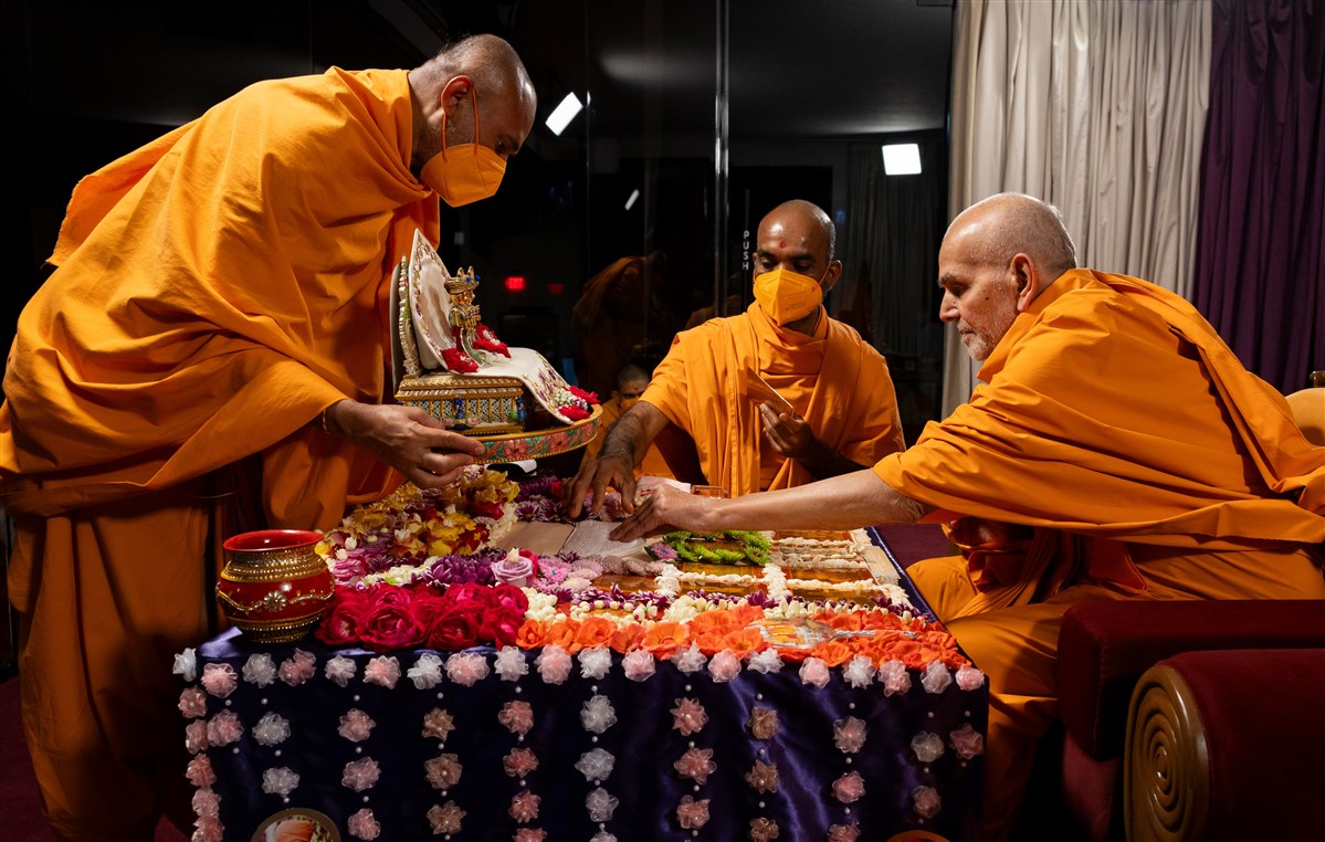 Swamishri helps in the placement of the Shri Harikrishna Maharaj and Shri Gunatitanand Swami Maharaj's murti