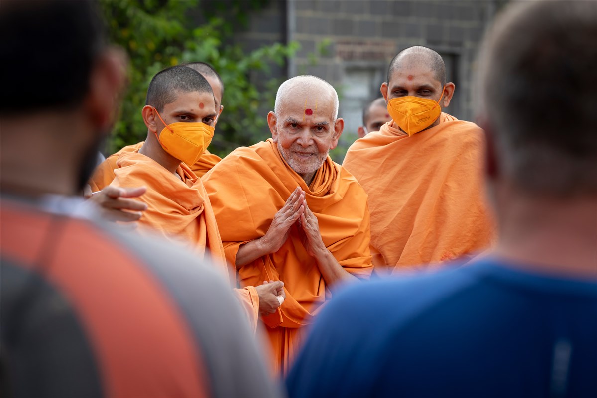 Swamishri folding hands to those present during the campus tour