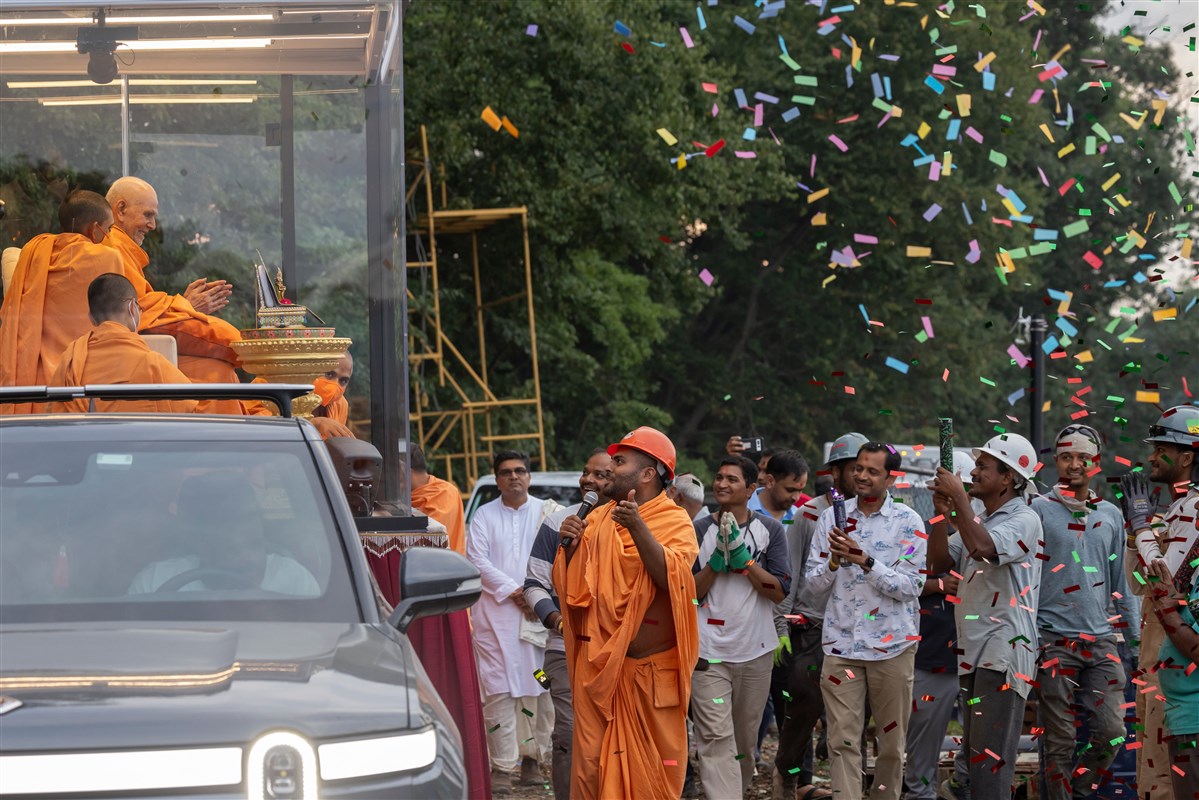Volunteers warmly welcome Swamishri with confetti as he enters their service area