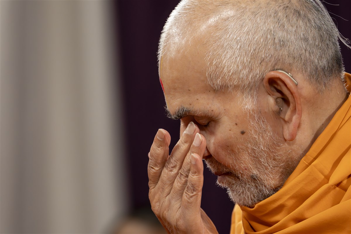 Swamishri reverently touches his eyes after touching the holy feet of Shri Akshar Purushottam Maharaj